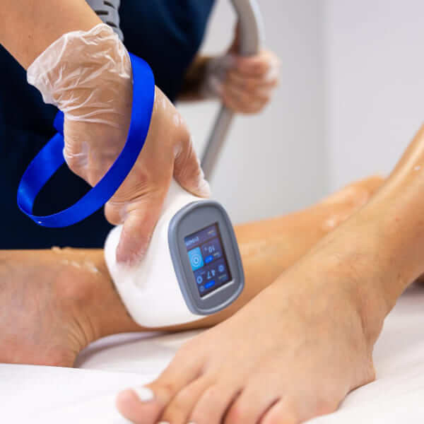 A medical professional wearing clear gloves uses a high-tech laser device to treat a patient's foot condition or nail fungus.
